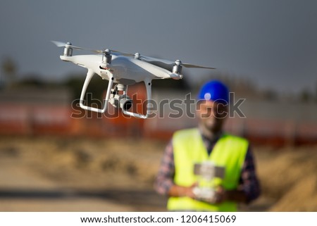Close up of drone flying at building site and construction worker with remote control in background