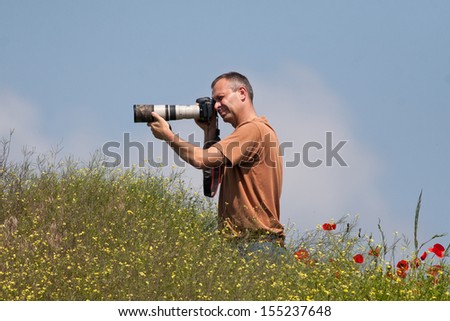 Photographer in action in poppy field