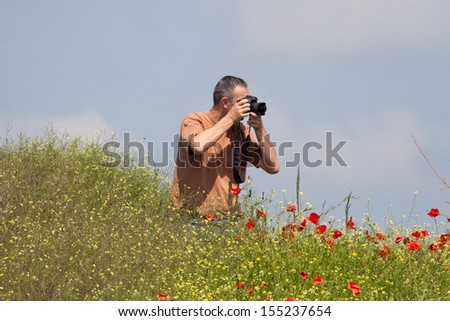 Photographer in action in poppy field