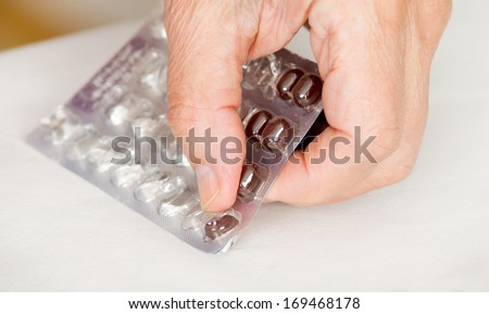 Close up of man\'s hand taking out pills from blister