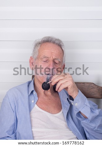 Old man lighting up smoking pipe with matches