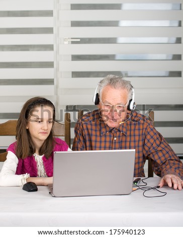 Granddaughter helping grandpa to make on line communication on laptop