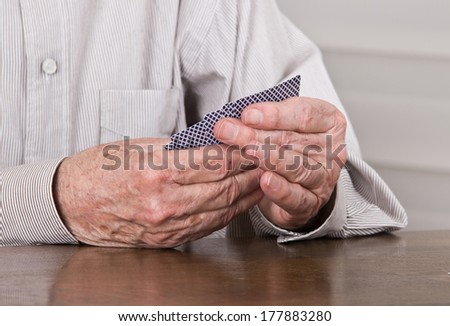 Close up of old man hands holding cards in game on table