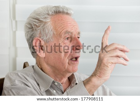 Wise old man talking with forefinger up in the air