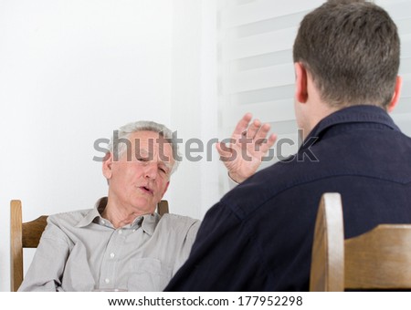 Old man with arm in the air telling stories to a young man