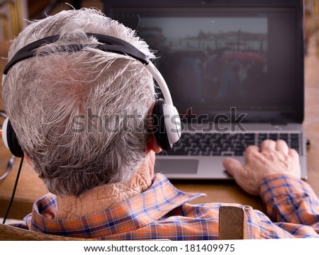 Old man with headset looking at laptop