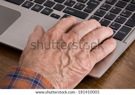 Close up of old man hand on keyboard of laptop