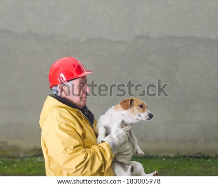 Old man in safety suit holds dog in his arms