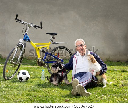 Senior man sitting on grass with dogs after bike ride