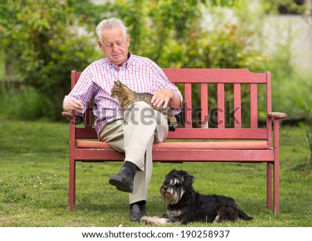 Old man with cat in lap and dog beside him