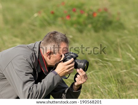 Photographer in action, flower shooting on meadow