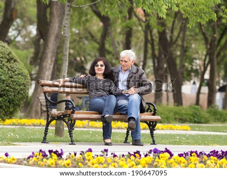 Older couple in hug sitting on bench in park