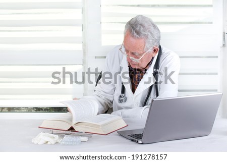 Experienced doctor researching in books and on internet in his office