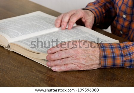 Close up of old man\'s hands holding a book