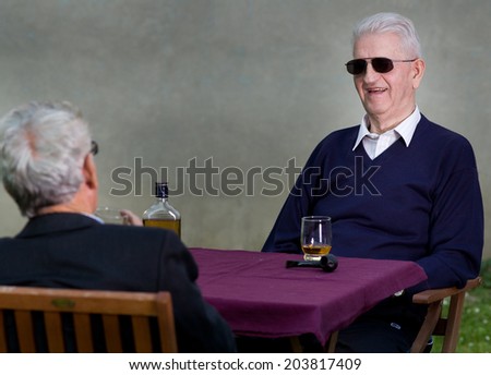 Two old man with sunglasses talking and smiling