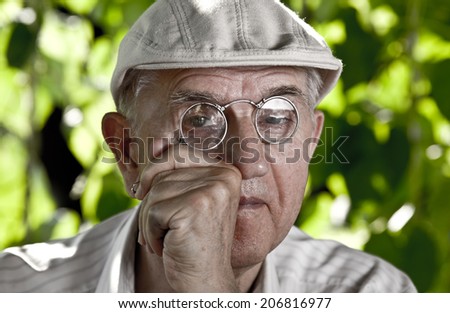 Old man investigator with reading glasses and cap