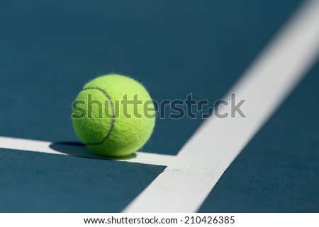 Tennis ball on blue hard court inside of line