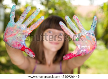 Young student girl showing colorful painted hands