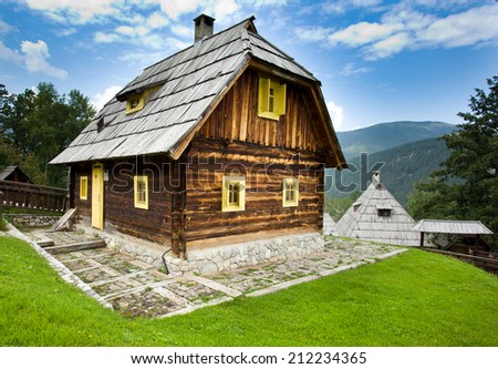 Traditional wooden cottage in mountain landscape and blue sky with clouds