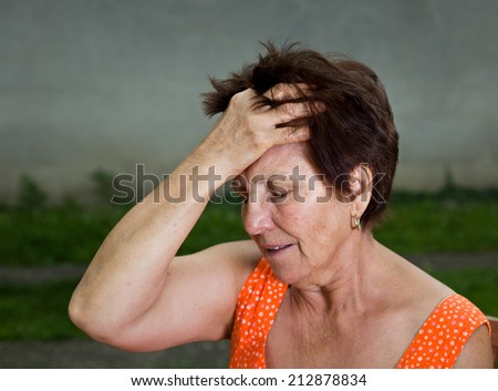 Senior woman suffers from headache, holding hand on head and have pain face