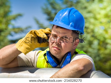 Tired worker with walkie talkie and safety equipment on oil plant Tired worker with walkie talkie and safety equipment on oil plant