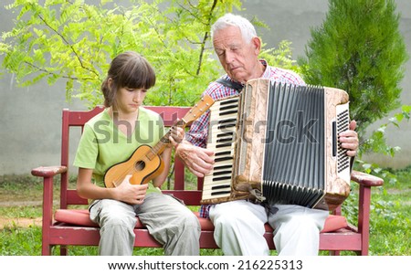 Girl and grandpa playing musical instruments in garden