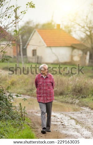 Senior man walking on dirty road in old village