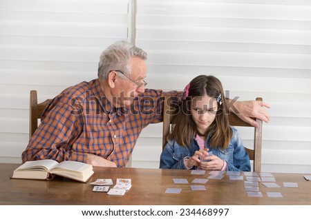 Grandpa and granddaughter playing memory game with cards