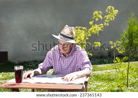 Old man reading newspapers in backyard at table