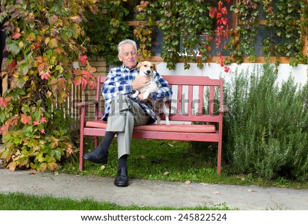 Senior man hugging his dog on his lap on bench