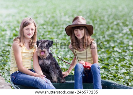 Two young girls sitting on boat with their dog