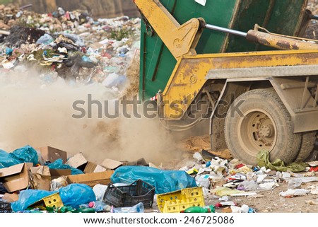 Truck tipping garbage from container on junk yard