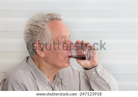 Close up of old man drinking blueberry juice