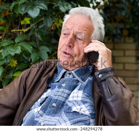 Old man in leather jacket talking on the cell phone