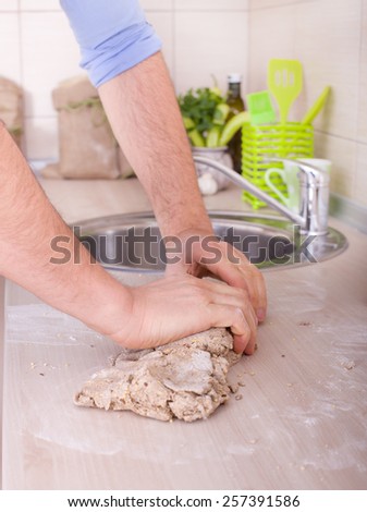 Male hand kneading dough of wholemeal bread on kitchen counter
