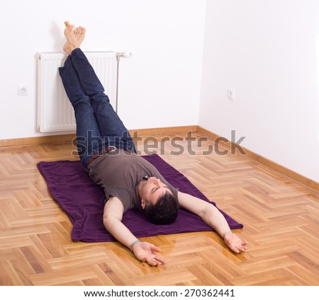 Man relaxing on the floor with his legs up on radiator on wall