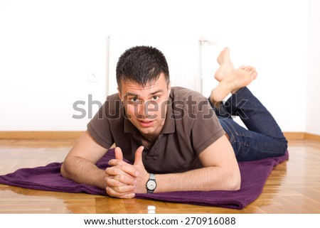 Attractive man lying on the floor on stomach  with legs up and looking at camera