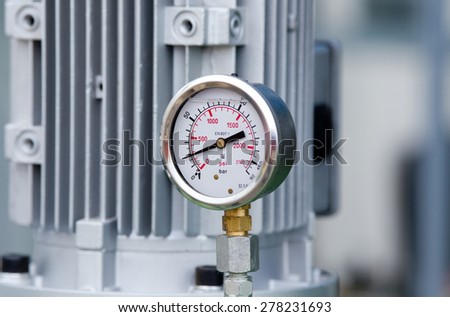 Close up of metal manometer with machinery in background