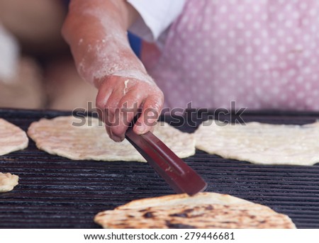 Close up of old woman\'s hand soiled with flour preparing flat bread on barbecue