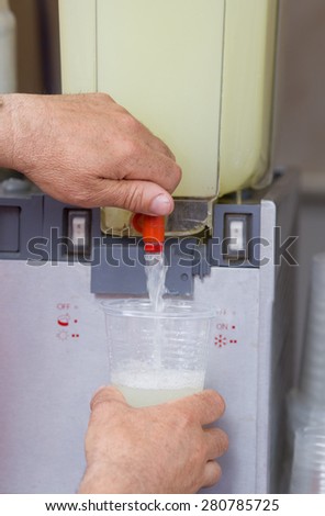 Close up of human hand pouring lemonade from juice machine