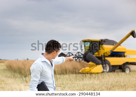 Young businessman pointing finger into combine harvester during harvest