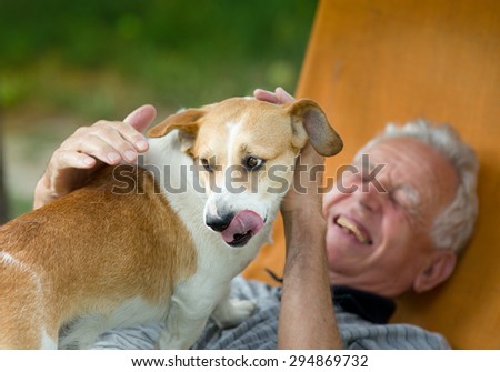 Senior man laughing while cute dog standing on his chest and licking