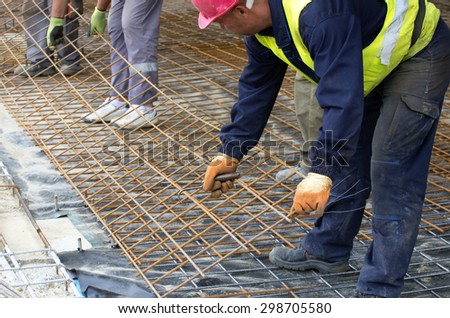 Construction workers installing reinforcement mesh at building site