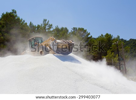 Bulldozer working on the top of huge pile of marble pebble on Thassos in Greece
