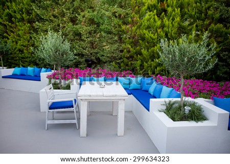 Luxury outdoor bar with white furniture and blue pillows in green environment