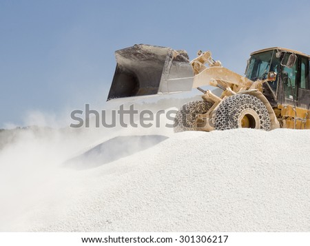 Bulldozer working on the top of huge pile of marble pebble on Thassos in Greece