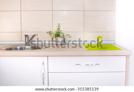 Wooden kitchen countertop with decorative mat, candles and herb against wall with beige tiles