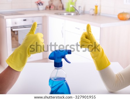 Close up of two workers gesturing ok sign after good job of cleaning in the kitchen