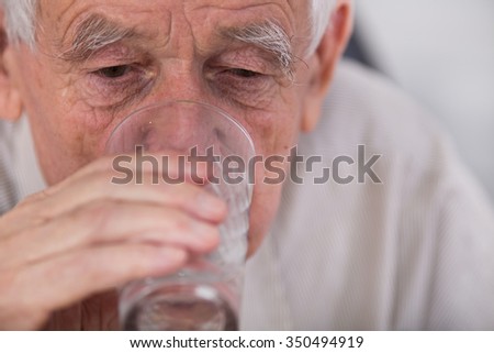 Close up of old man drinking water from glass