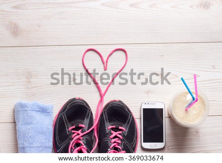 Sport concept, healthy lifestyle. Female sport shoes, towel, cell phone and smoothie in the cup on the floor, ready for jogging. Top view